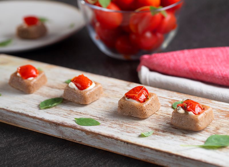 Blinis quadrado de azeitonas pretas, creme defumado e tomate confit